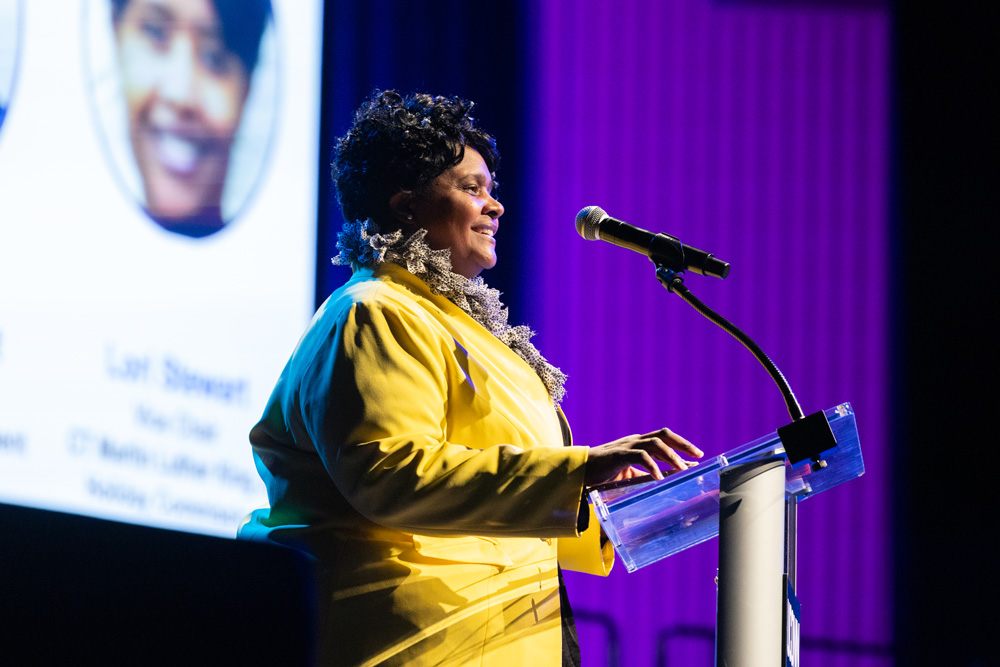 Speaker at a podium presenting on stage during a UConn event.